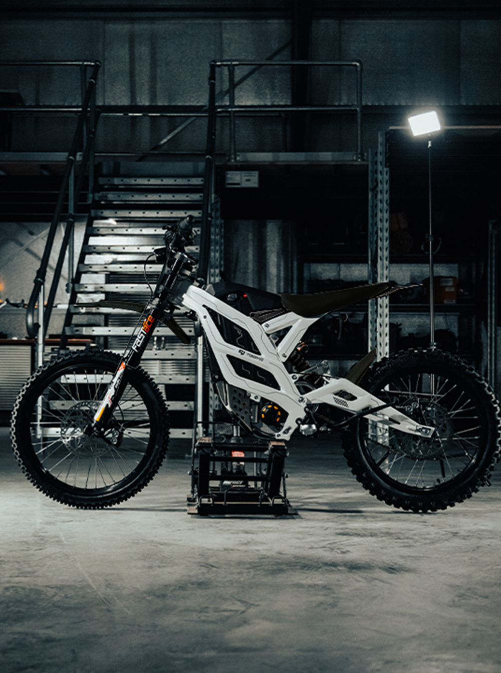 Falcon GT Arctic White de profil dans un atelier industriel